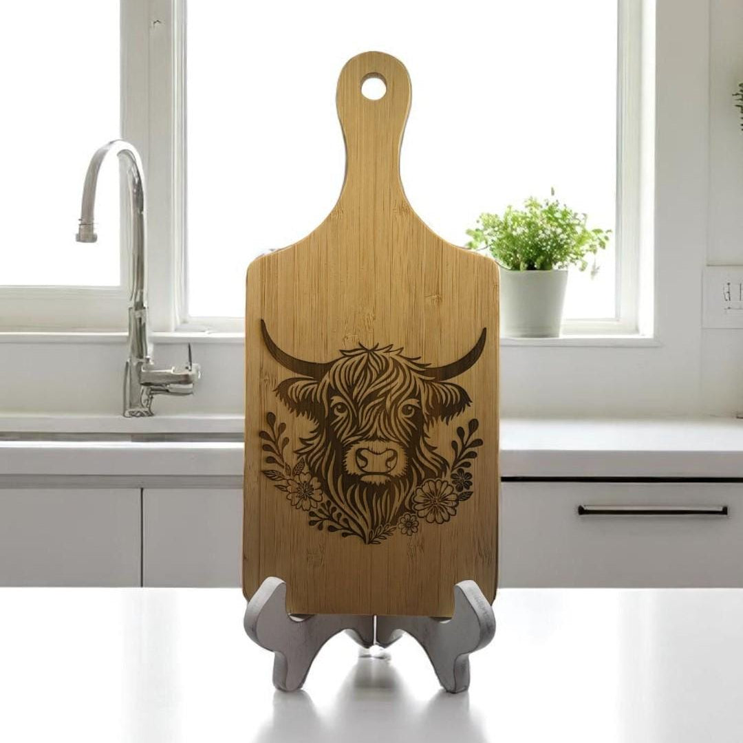 Wooden cutting board with a cow design on a stand in a kitchen.