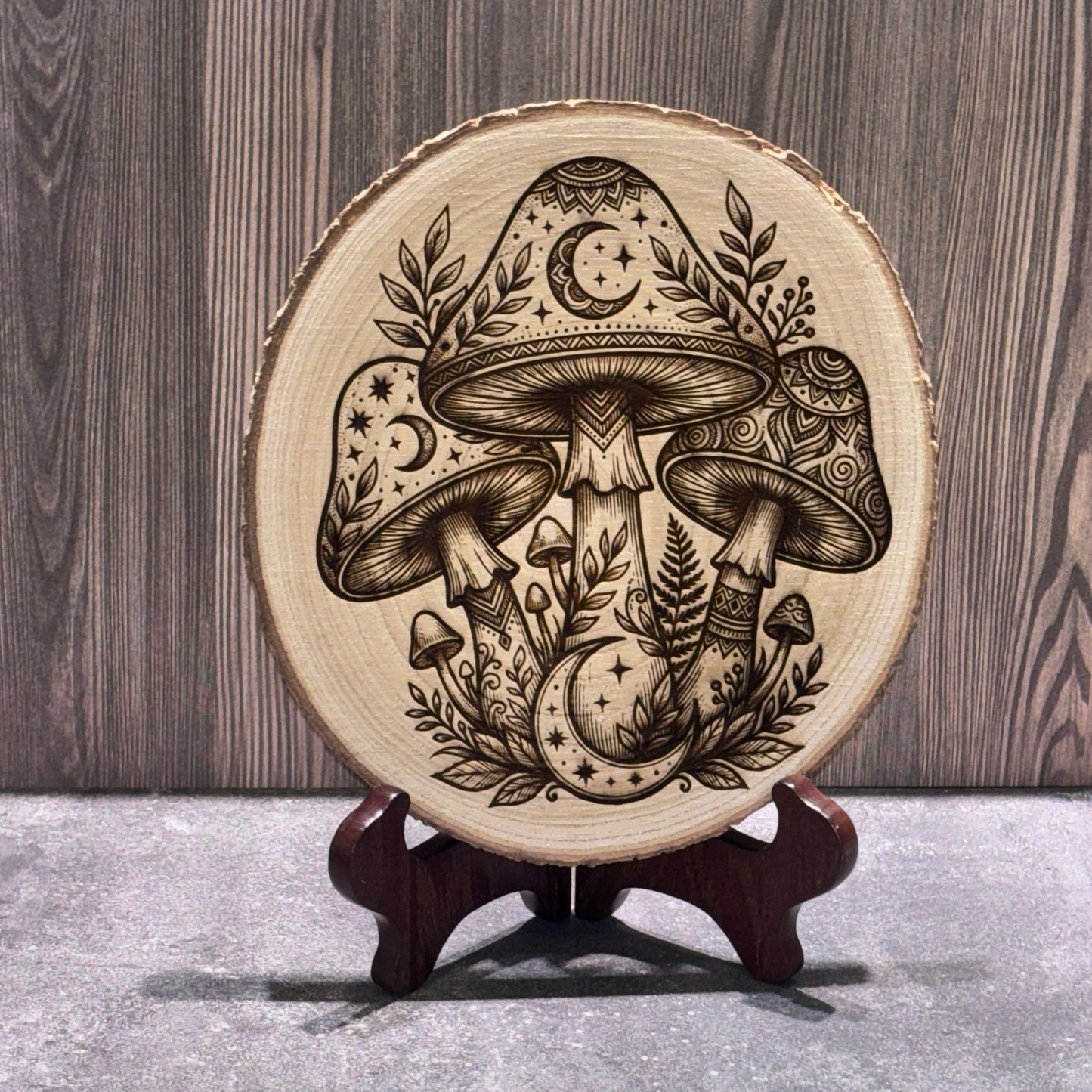 Natural 8 to 9 inch wood slice engraved with detailed mushrooms, crescent moons, stars, and botanical accents. Stand not included.
