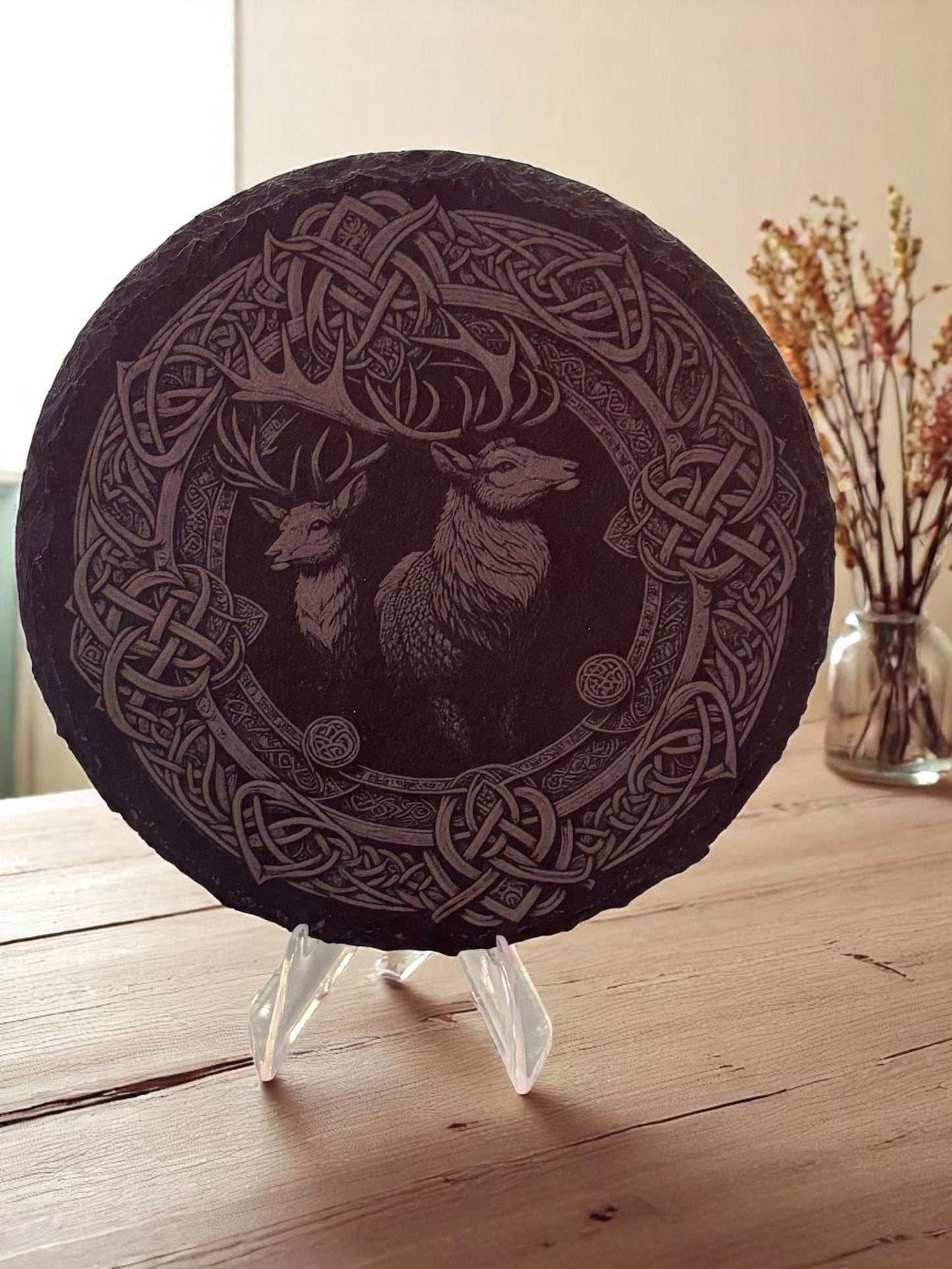 Decorative plate with Celtic knot design and deer illustration on a stand.