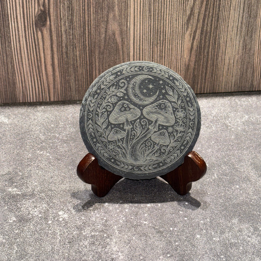 Decorative slate coaster with intricate design on a concrete floor.