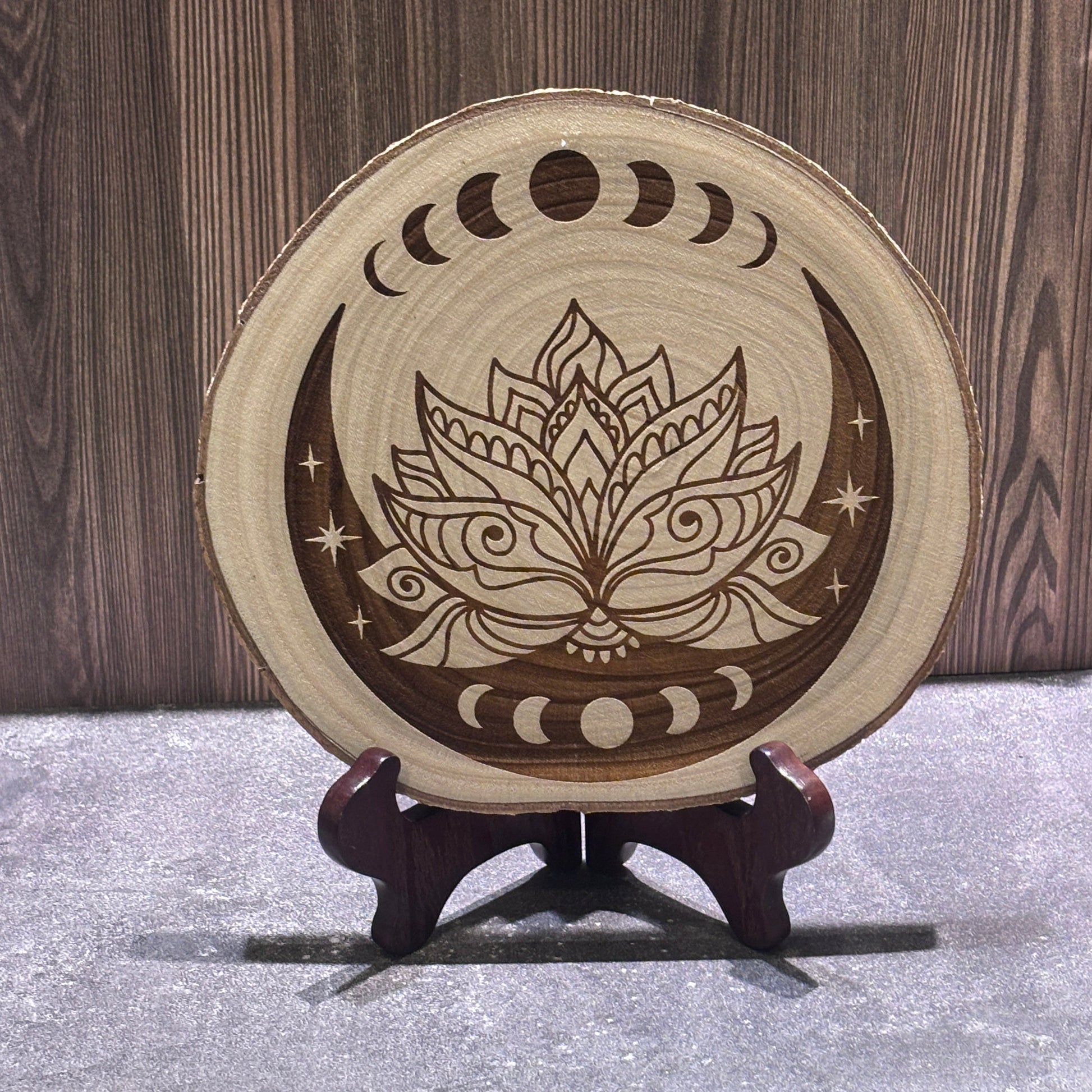 Natural 8 to 9 inch wood slice engraved with a lotus flower surrounded by moon phases, crescent moons, and stars. Stand not included.