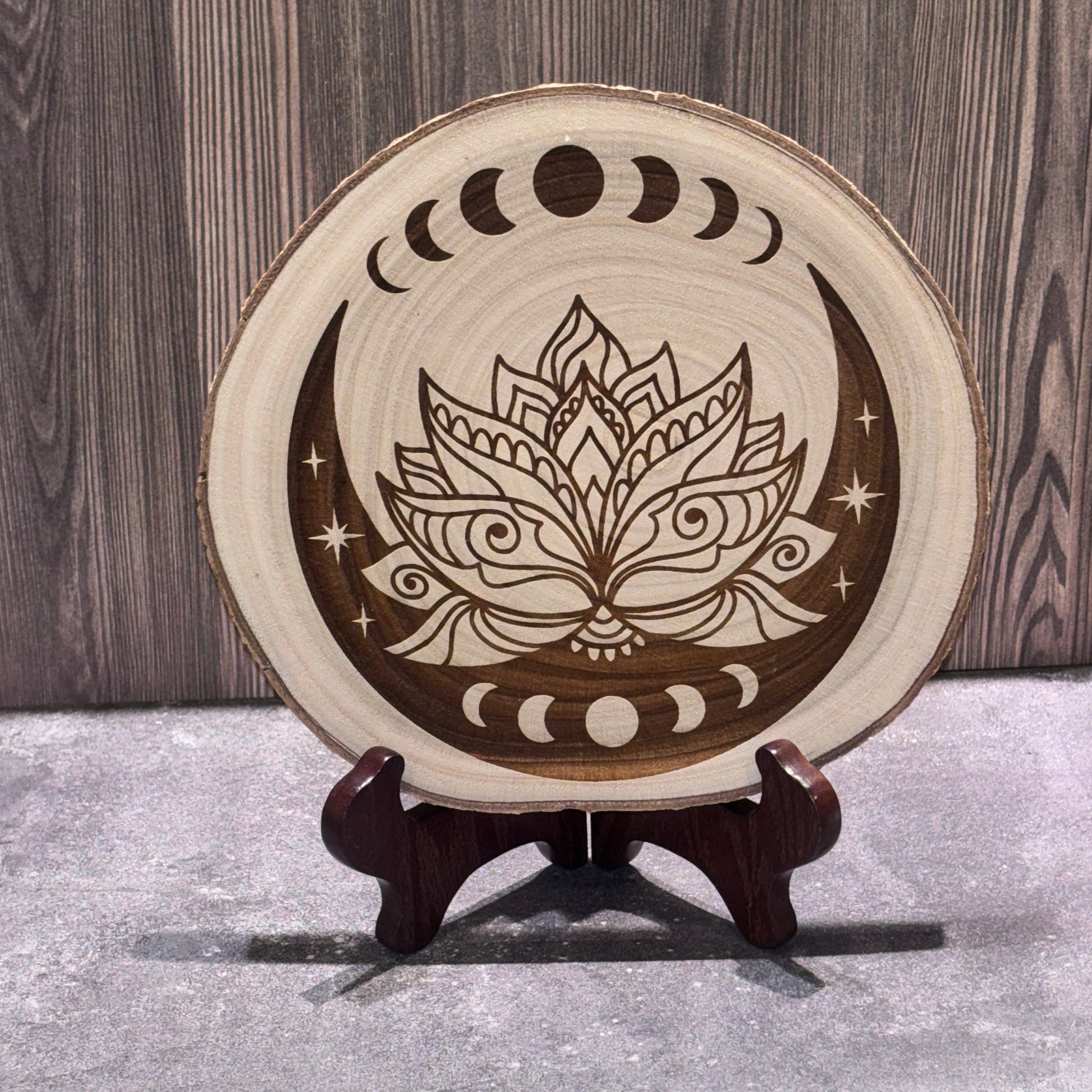 Natural 8 to 9 inch wood slice engraved with a lotus flower surrounded by moon phases, crescent moons, and stars. Stand not included.