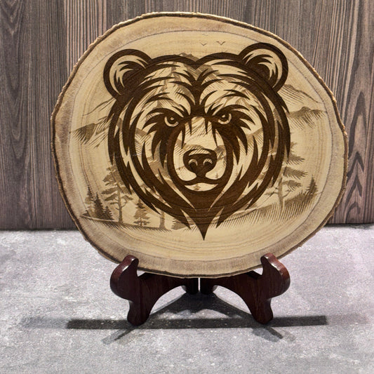 Natural 8 to 9 inch wood slice engraved with a bear portrait over a mountain and forest landscape. Stand not included.