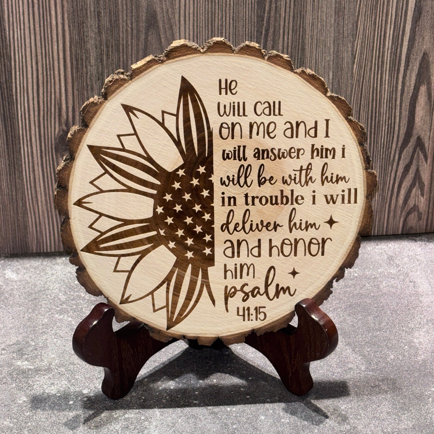 Natural 8 to 9 inch wood slice engraved with a patriotic sunflower featuring an American flag design and Psalm 91:15 scripture. Stand not included.